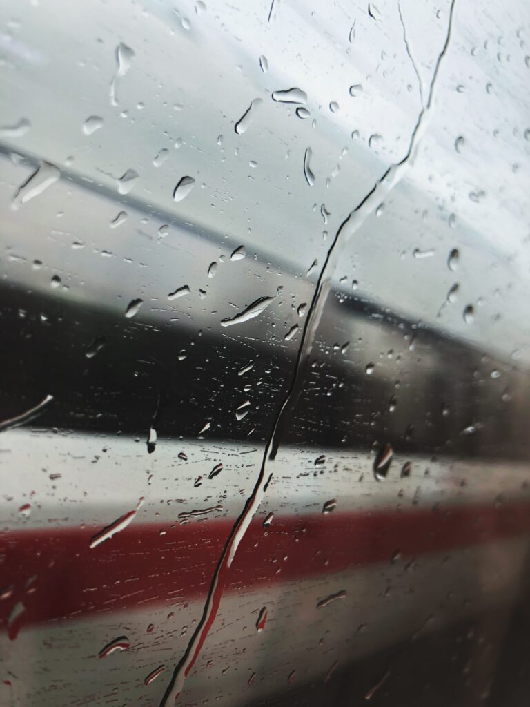 Rainy Ambiance Wallpaper: Water Droplets on Glass with Train Blurred