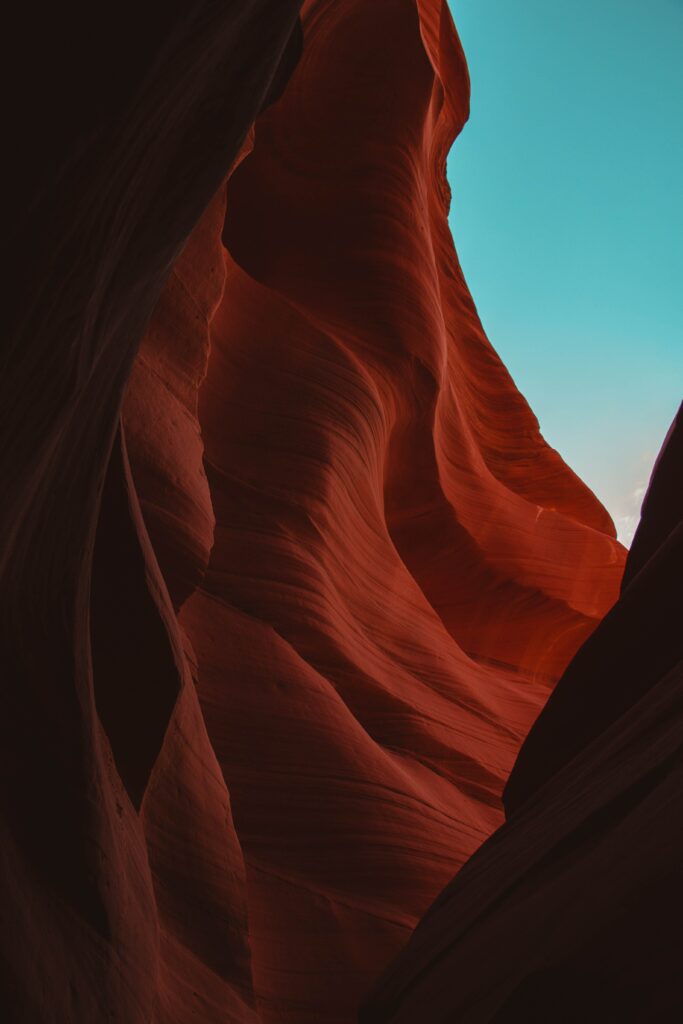 Stunning wavy red and orange canyon walls with deep textures under clear blue sky wallpaper background