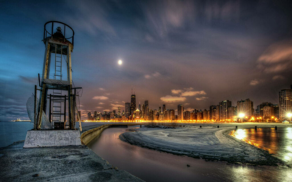 Weathered lighthouse by Lake Michigan with vibrant Chicago skyline under twilight sky wallpaper