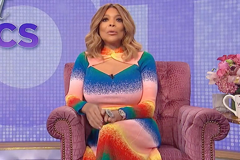 Wendy Williams hosting in vibrant multicolored dress on plush chair with stylish studio backdrop Wallpaper