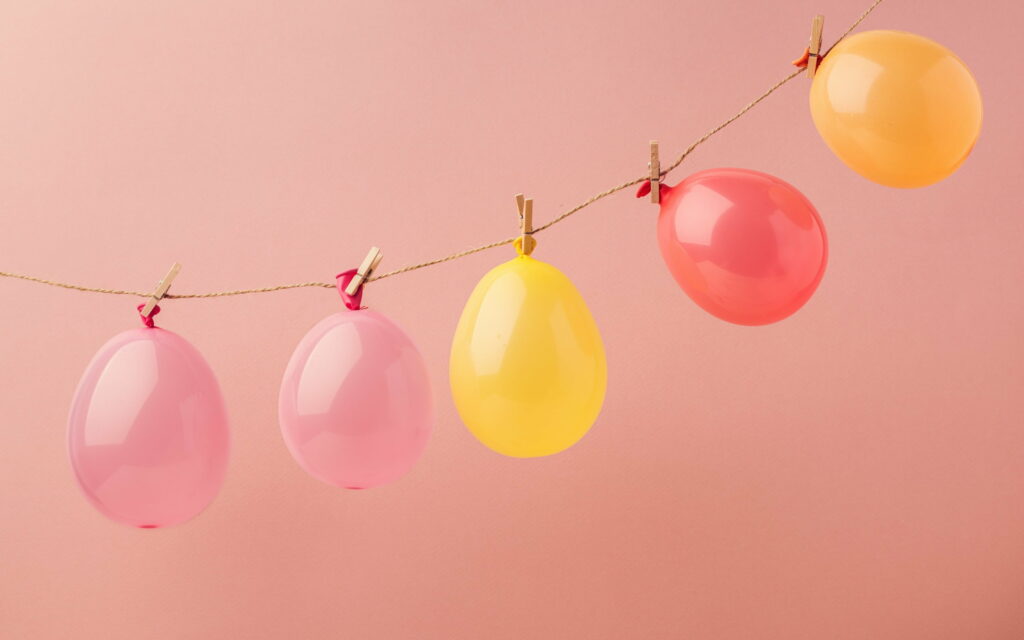 Whimsical Balloon Garland: Vibrant Colors and Playful Decor on a Stunning Pink Background Wallpaper