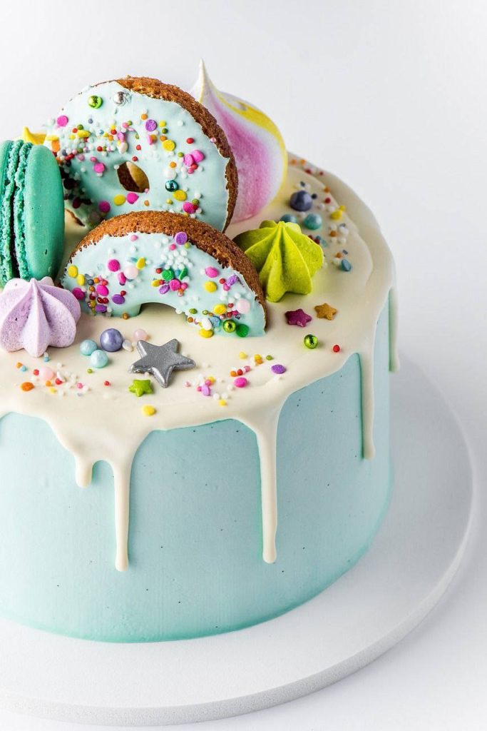 Phone wallpaper with cake, blue frosting, white drip icing, donut, green macaroons, meringues, stars