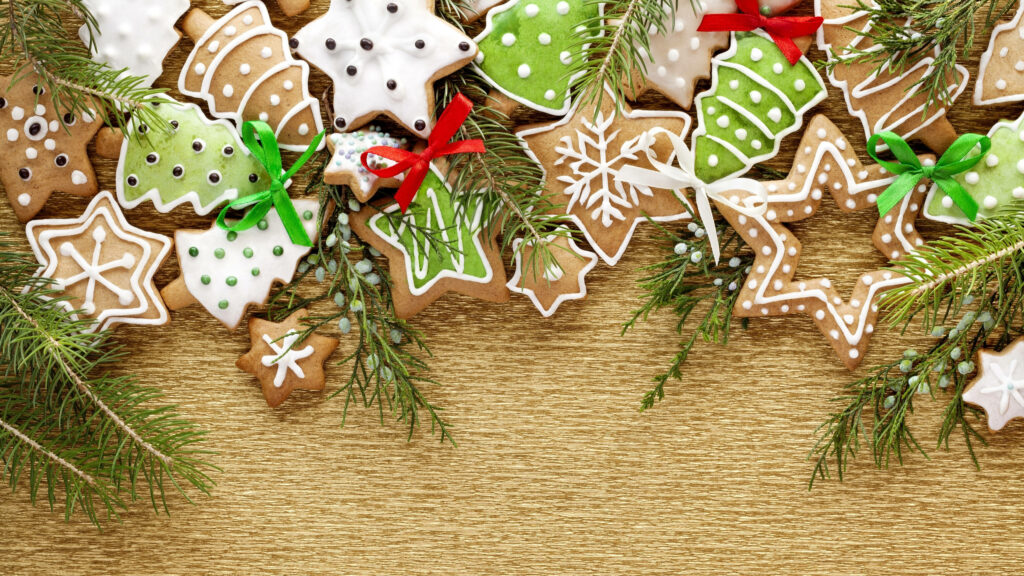 Festive Holiday Delights: Whimsical Christmas Cookie Artistry Adorning Rustic Wooden Table Wallpaper