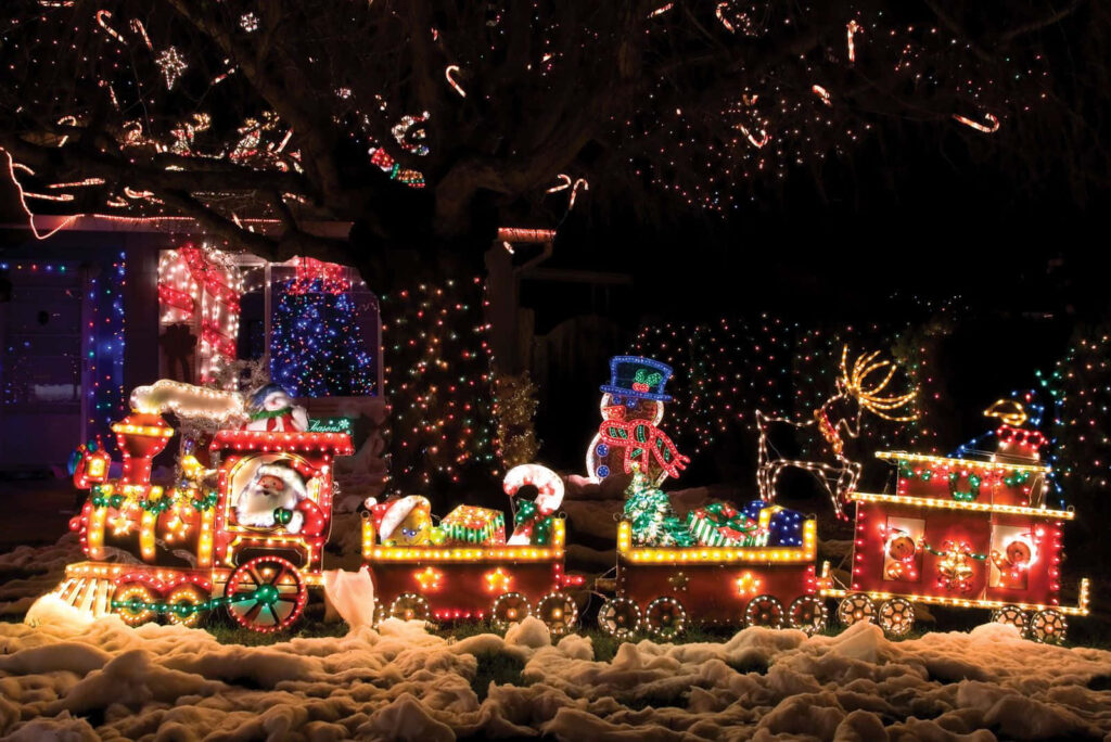Whimsical Christmas Eve: Festive Train in Snowy Village Wonderland Wallpaper