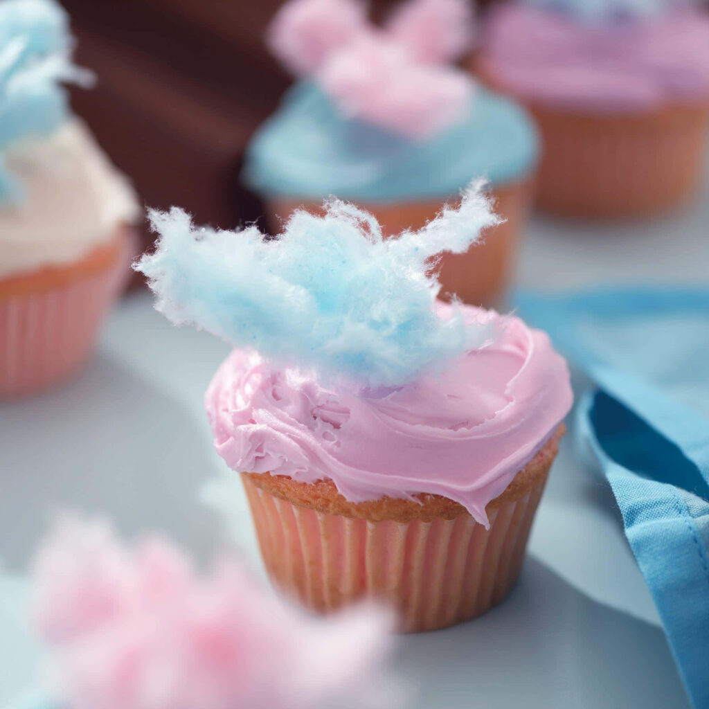 Sugary Sweet Delights: A Delectable Composition of Pastel Pink Cotton Candy Cupcakes on a White Surface, Enlivened by a Bokeh Background Wallpaper