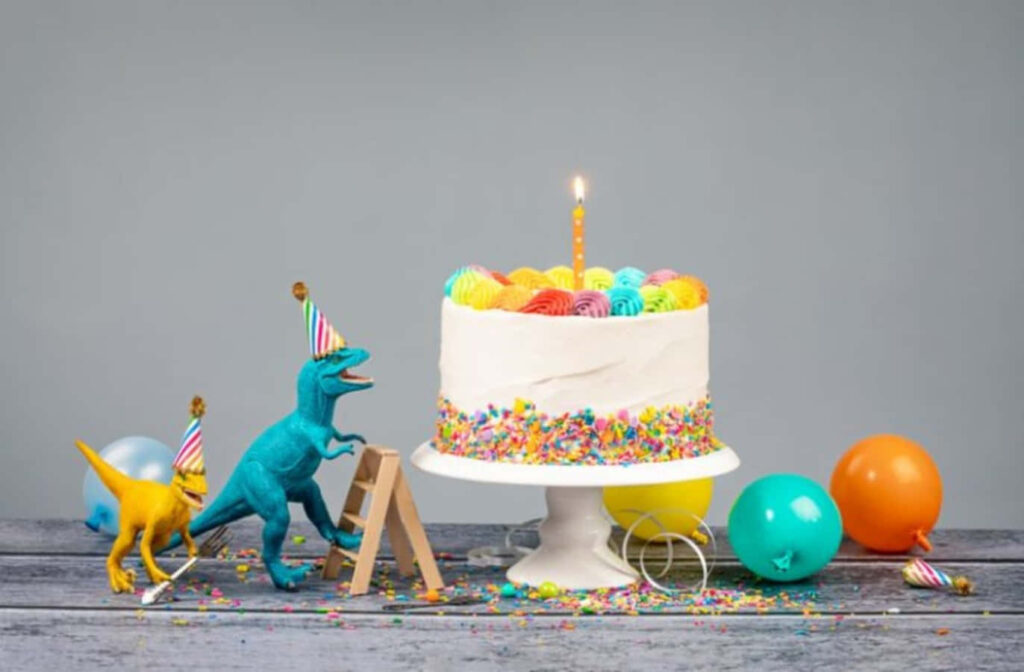 Playful Dinosaurs Celebrate with Birthday Cake & Colorful Balloons Wallpaper
