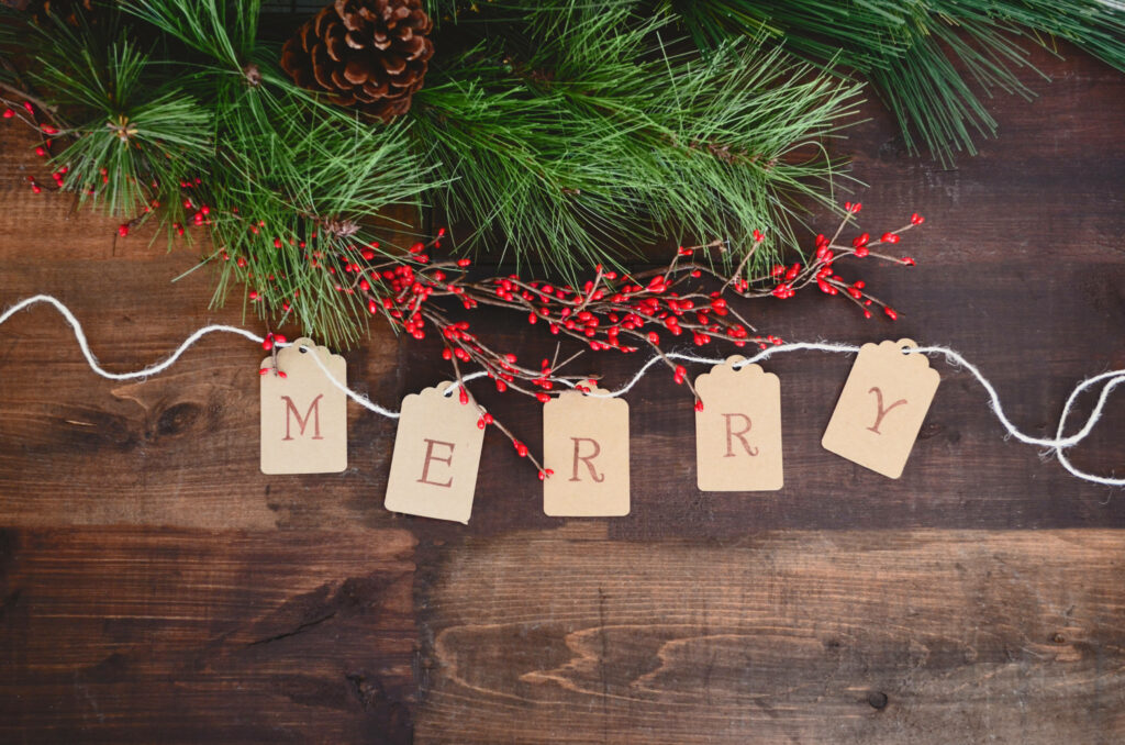 Festive Flat Lay Delights: Adorable Christmas Cutout Hangs from String near Wreath on Rustic Wooden Table Wallpaper