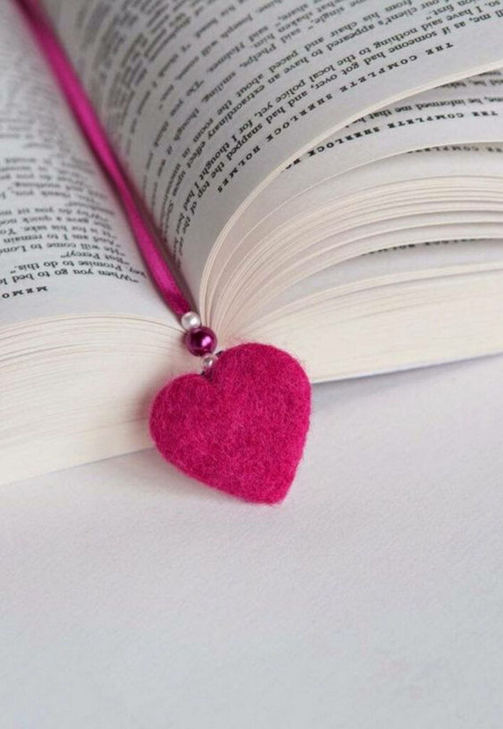 Charming Pink Heart Bookmark Set in a Tranquil Book Scene on a Minimalist White Surface Wallpaper