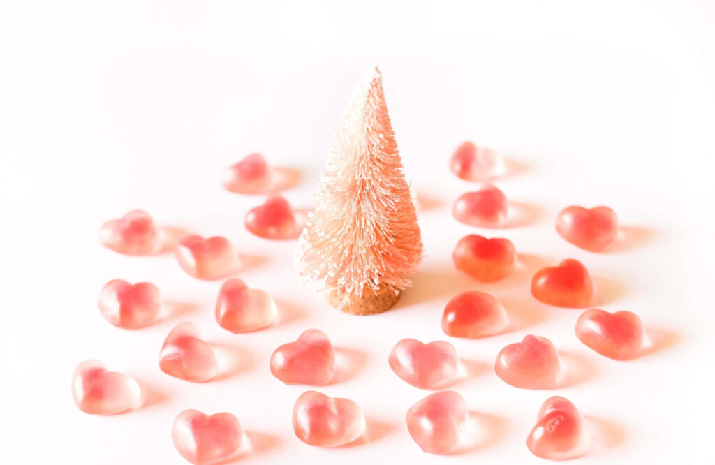 Whimsical Miniature Tree with Pink Heart Decorations on White Background Wallpaper
