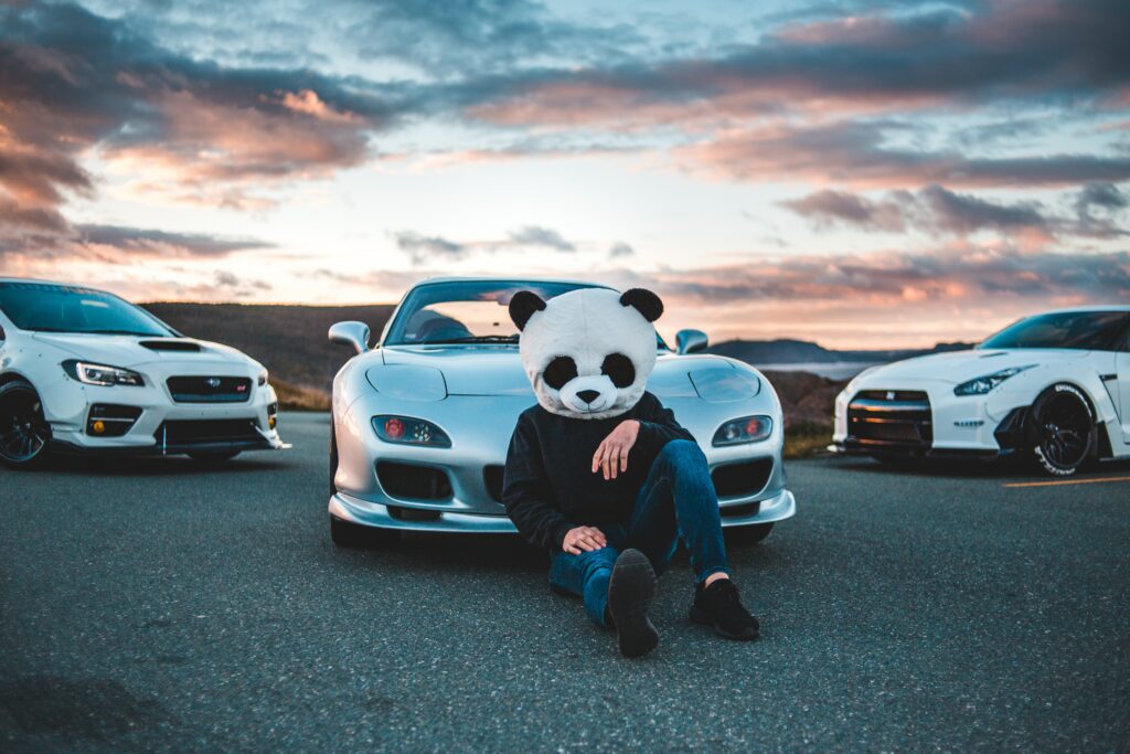 Panda Mask Adventurer with Mazda: Vibrant Sunset Racing Scene Wallpaper