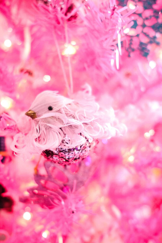 Whimsical Pink Christmas Tree Wallpaper with Bird Ornament Glow