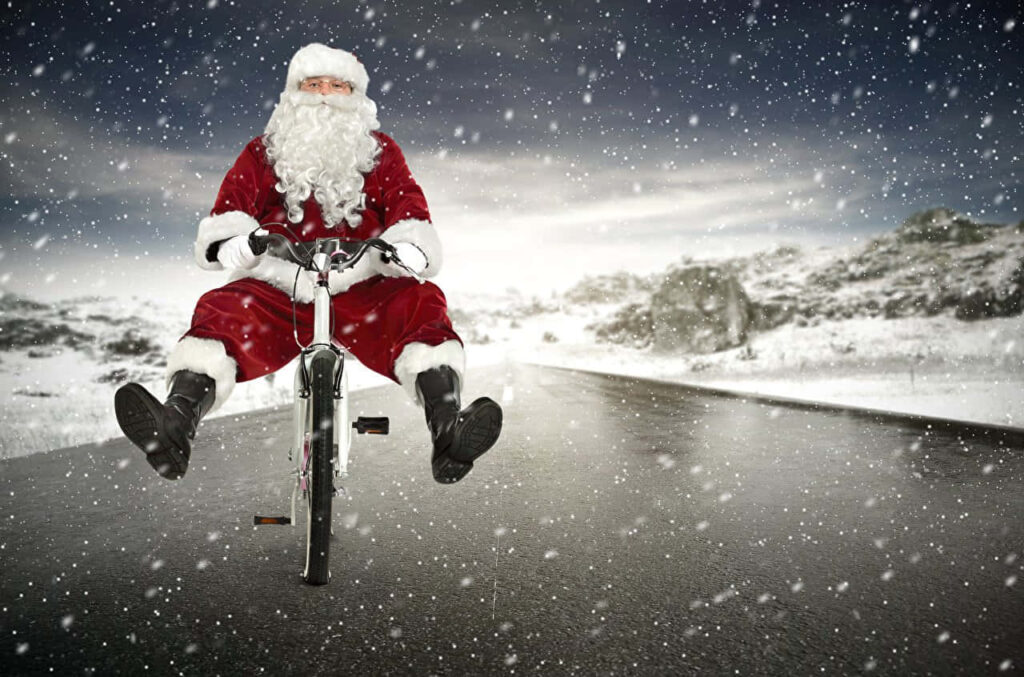 Santa Claus Joyfully Biking in a Snowy Winter Wonderland Wallpaper