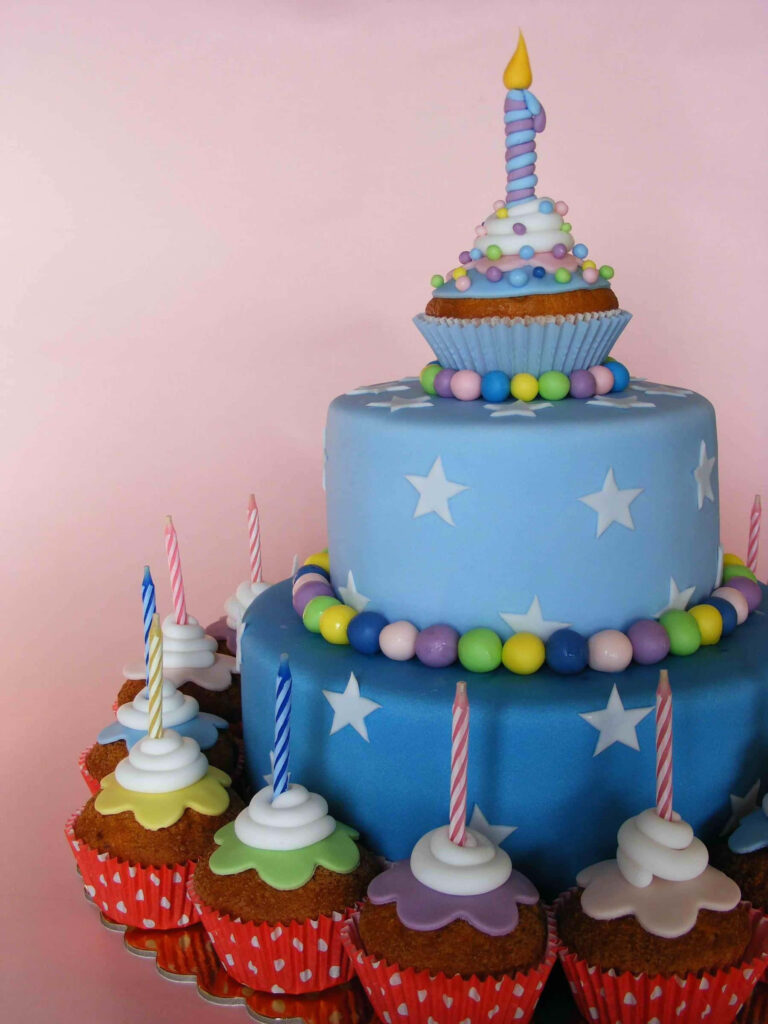 Whimsical Blue Cake & Cupcakes with Stars on Soft Pink Background Wallpaper