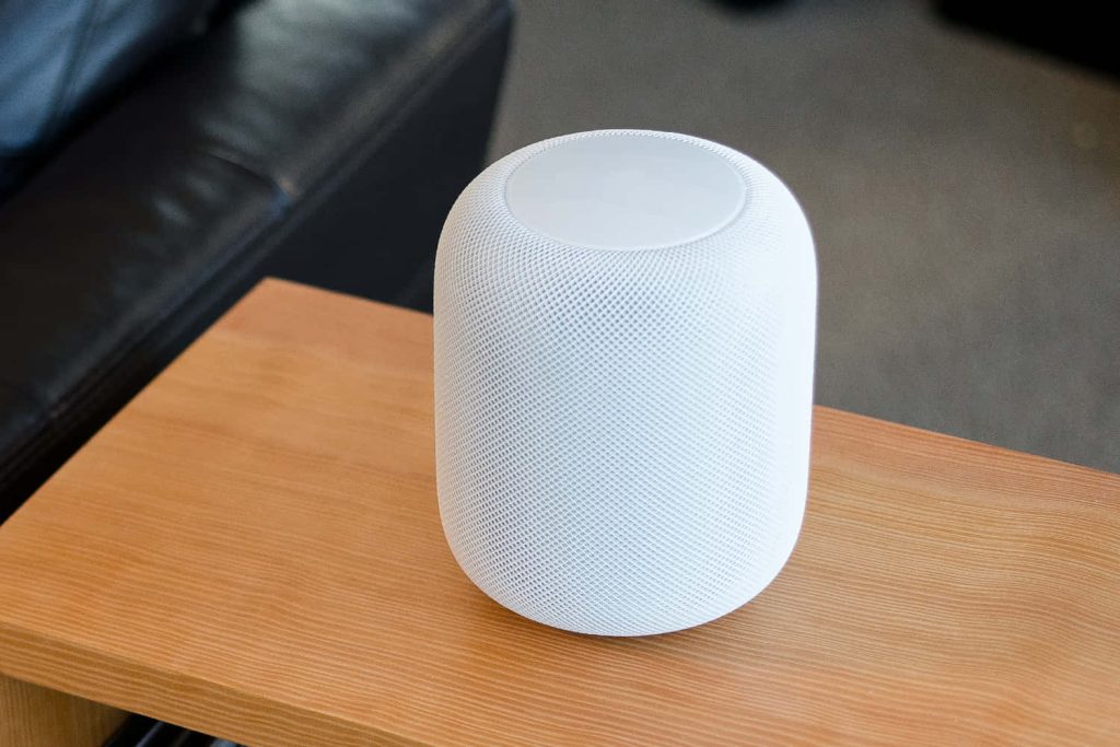 White Apple HomePod on light wooden surface with mesh fabric in soft natural light background Wallpaper