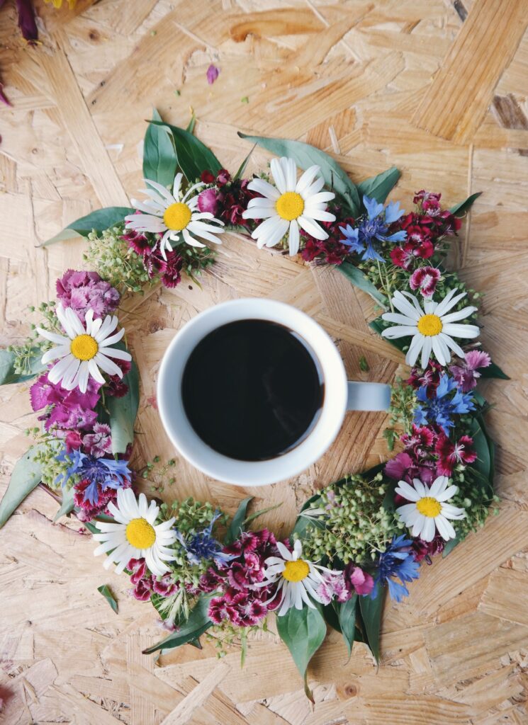 Stunning Floral Wreath Surrounds White Coffee Cup on Wood Wallpaper