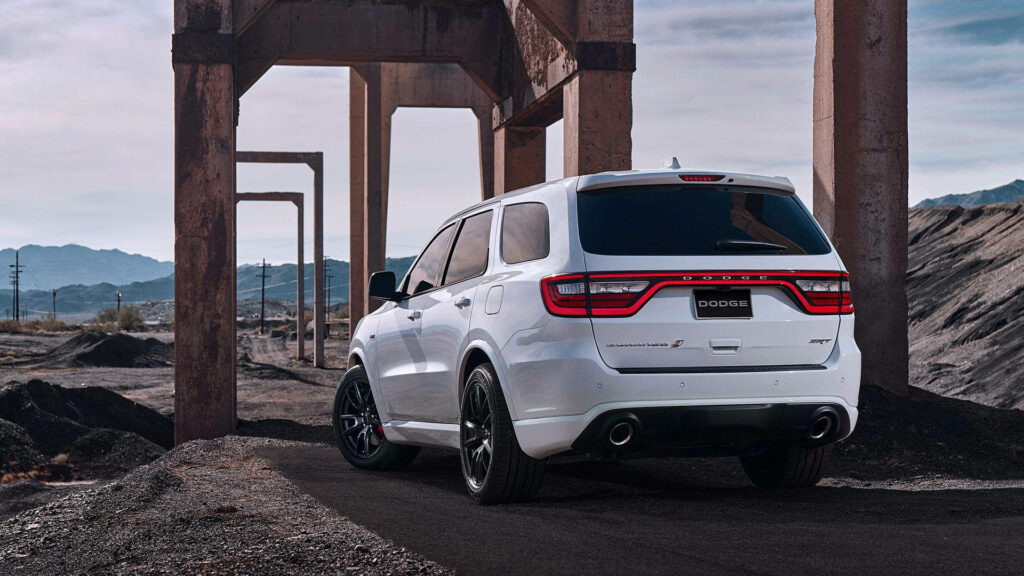 White Dodge Durango parked under concrete structures in rugged desert mountains adventure wallpaper