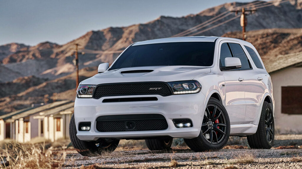 White Durango SUV parked before rugged mountains showcasing adventure and power outdoors Wallpaper
