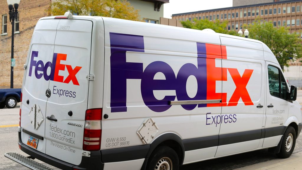 White FedEx Express delivery van with purple orange logo in bright urban cityscape background Wallpaper