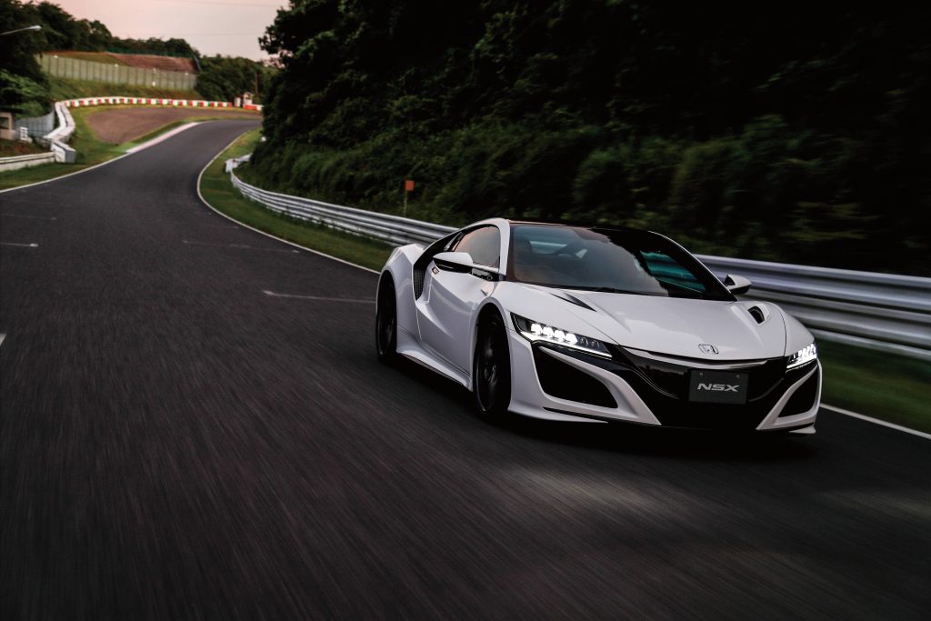 White Honda NSX cornering fast on racetrack with motion blur and sharp LED headlights Wallpaper