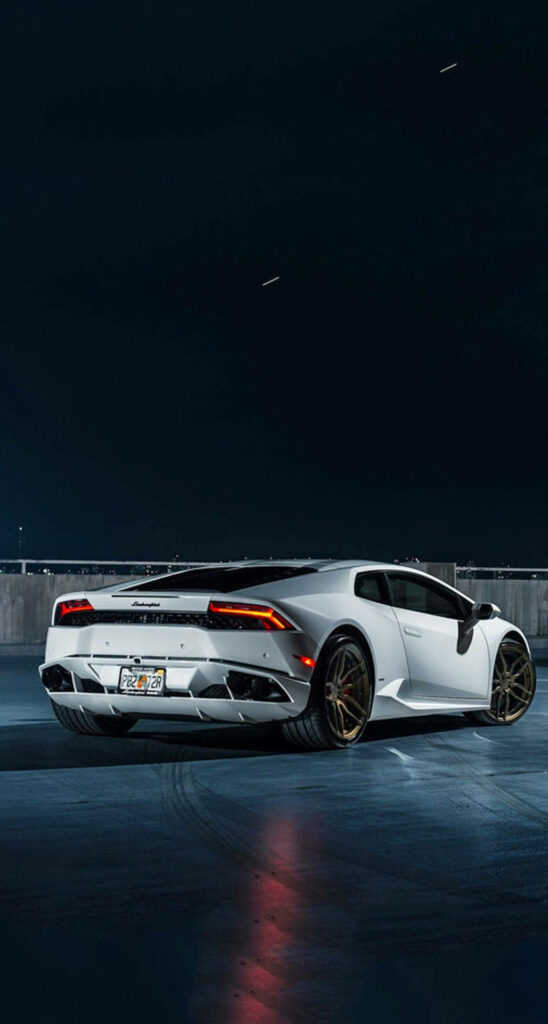 White Lamborghini with gold rims parked in modern city at night perfect iPhone wallpaper background