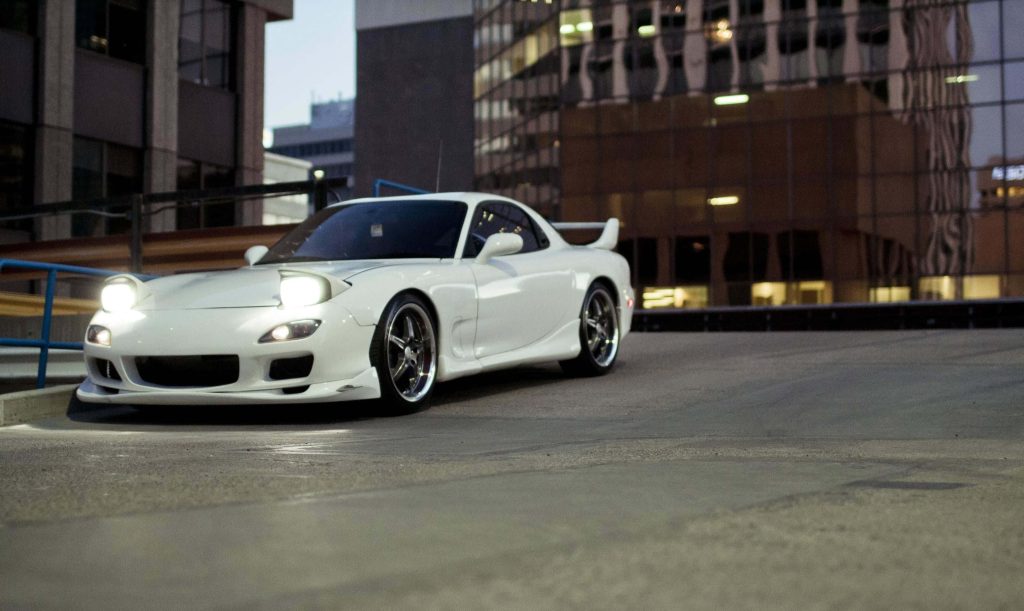 White Mazda RX-7 FD JDM sports car with pop-up headlights on urban rooftop at twilight Wallpaper