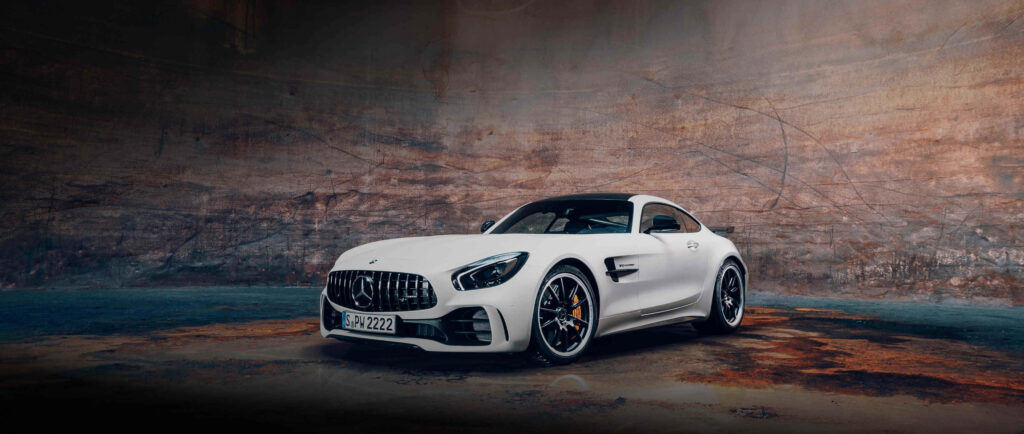 White Mercedes AMG GT R parked inside rugged cave showcasing sleek powerful design wallpaper