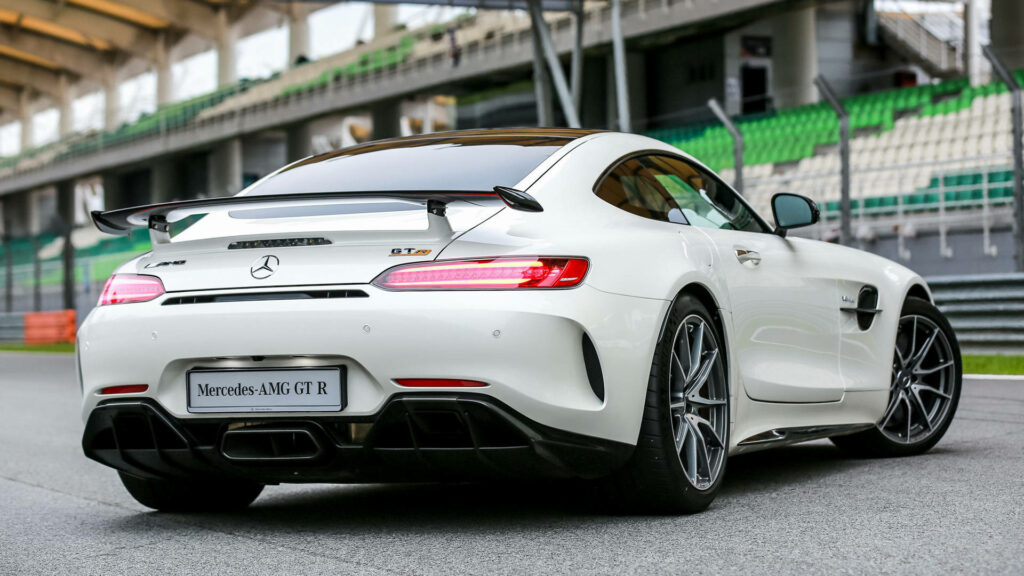 Rear view of white Mercedes AMG GT R on racetrack with sporty design and aerodynamic spoiler Wallpaper
