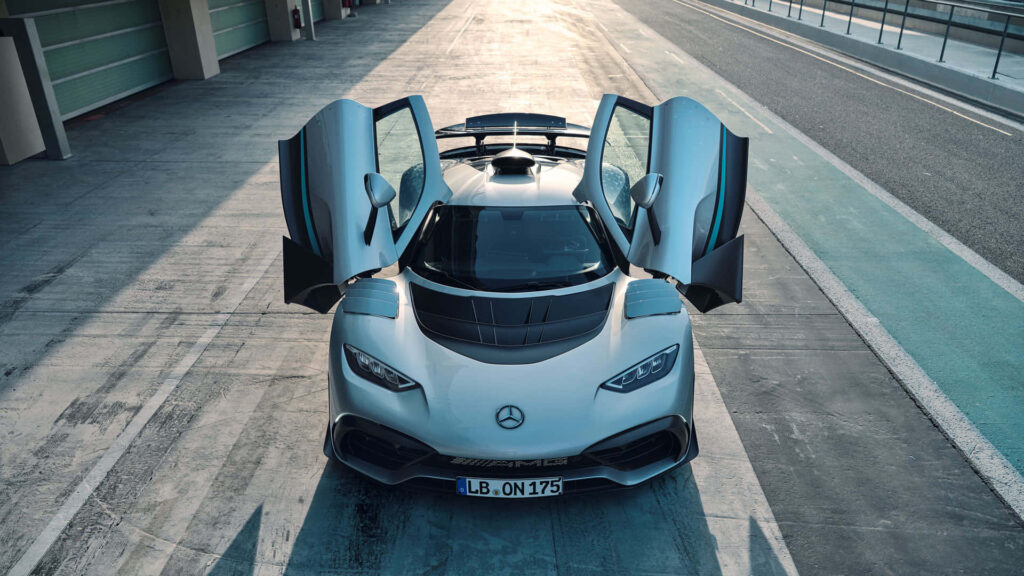 White Mercedes-AMG sports car with gullwing doors open on sunlit racetrack showcasing design Wallpaper