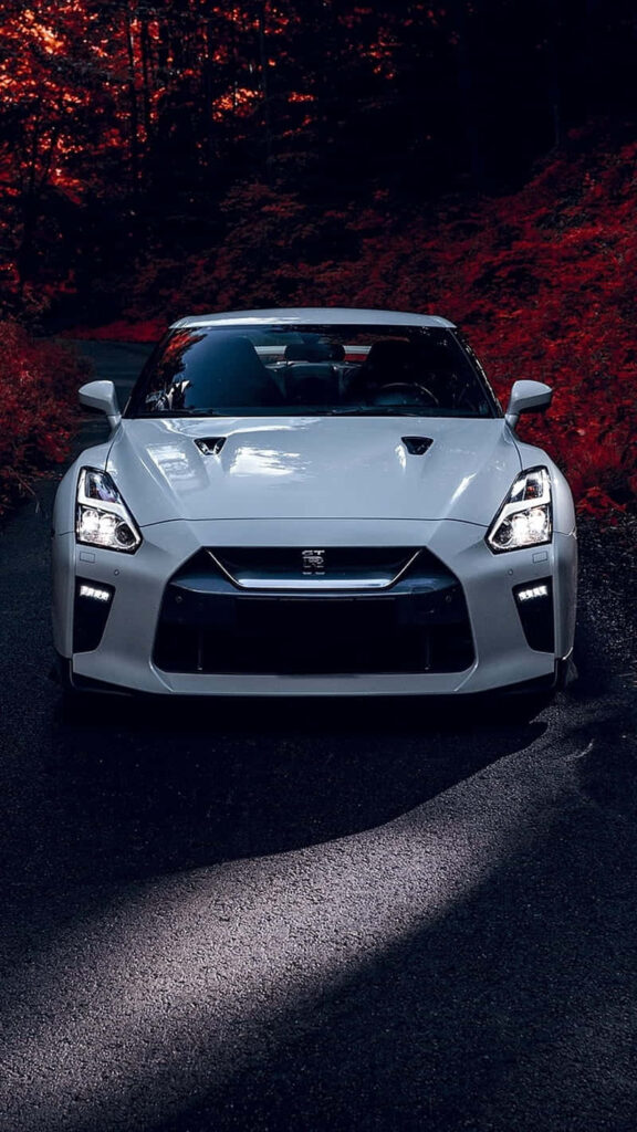 White Nissan R35 GTR front view sleek design vibrant red forest background automotive wallpaper