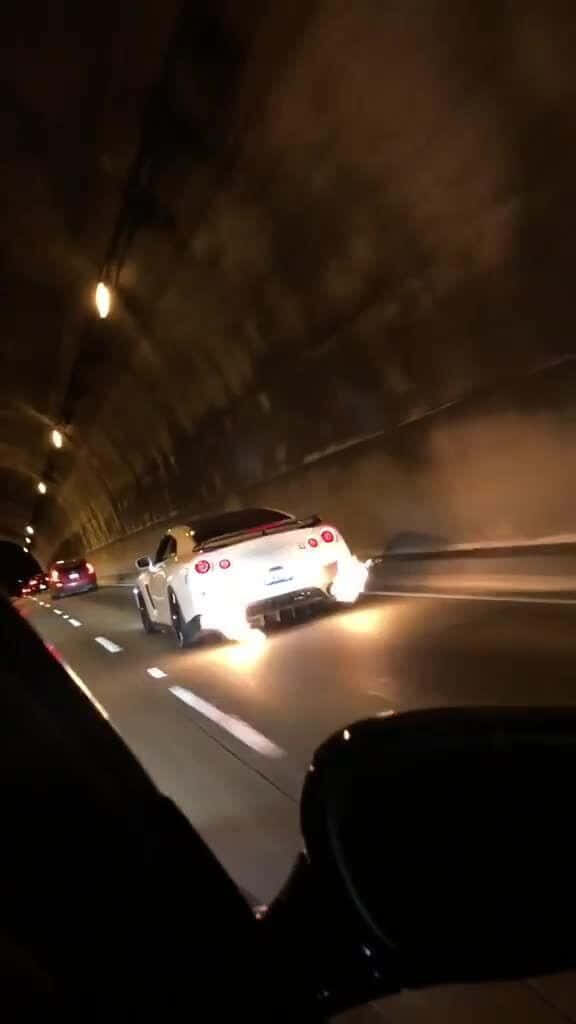 White Nissan R35 GTR speeding through dim tunnel with flames from exhaust at night wallpaper