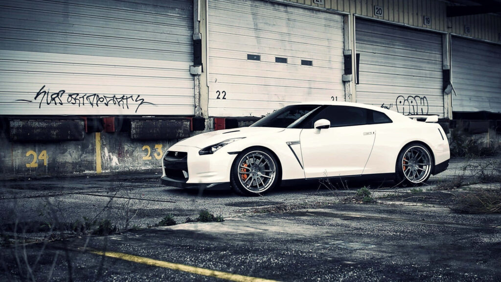 White Nissan R35 GTR sports car parked by old industrial loading dock urban wallpaper background