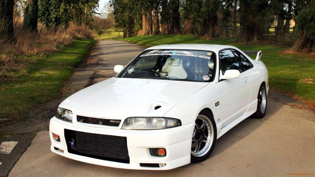 White Nissan Skyline GT-R R33 with aggressive bumper and intercooler in peaceful tree-lined background Wallpaper