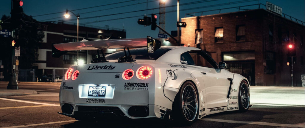 White Nissan Skyline GTR R34 rear view at night with custom decals big spoiler urban street wallpaper