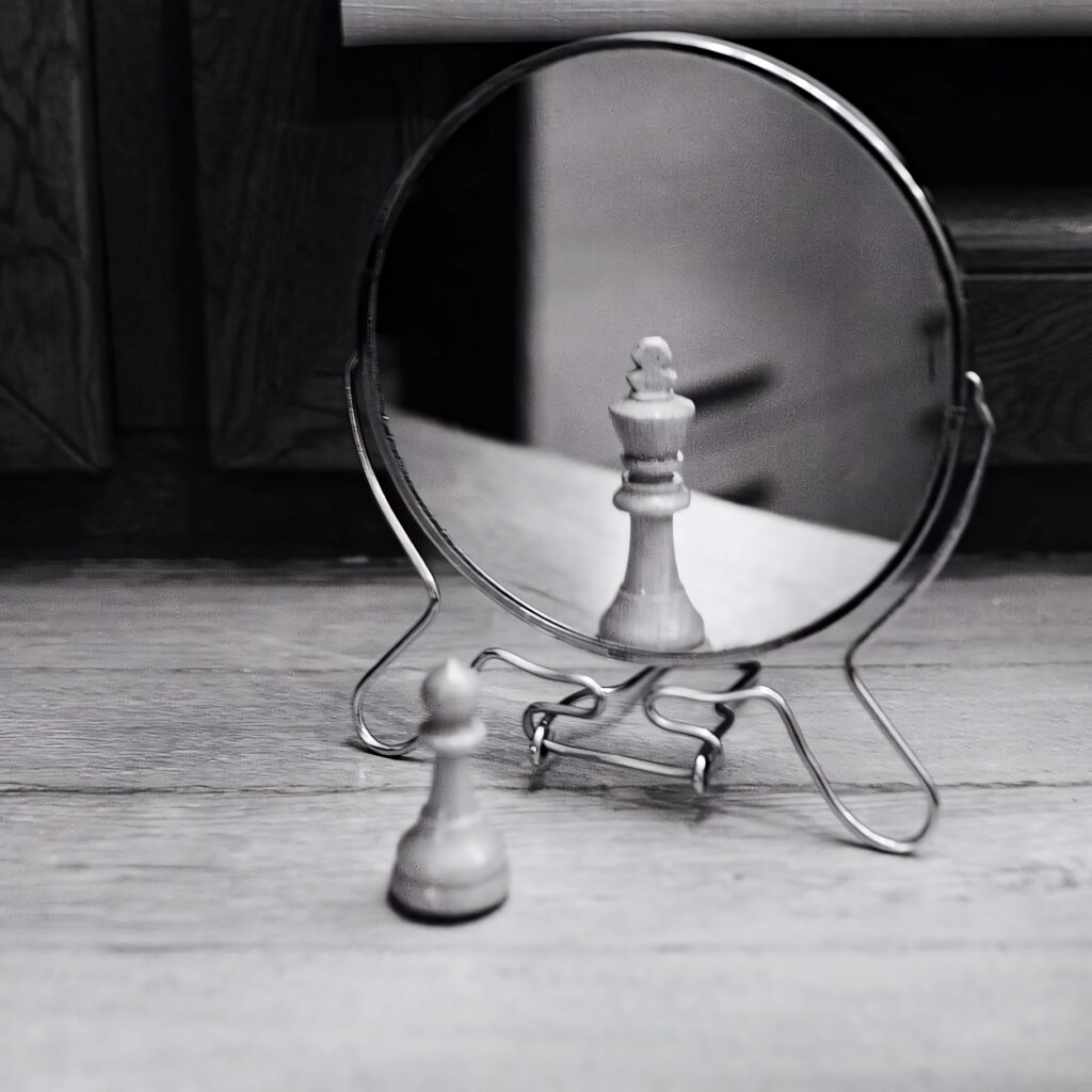 White pawn on wood reflected as king in mirror grayscale chess wallpaper symbolizing aspiration