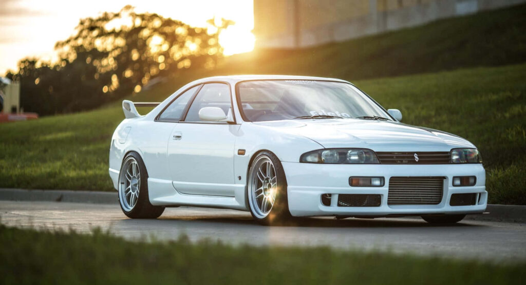 White R33 GTR low ride height parked on smooth road with sunset and green scenery background Wallpaper