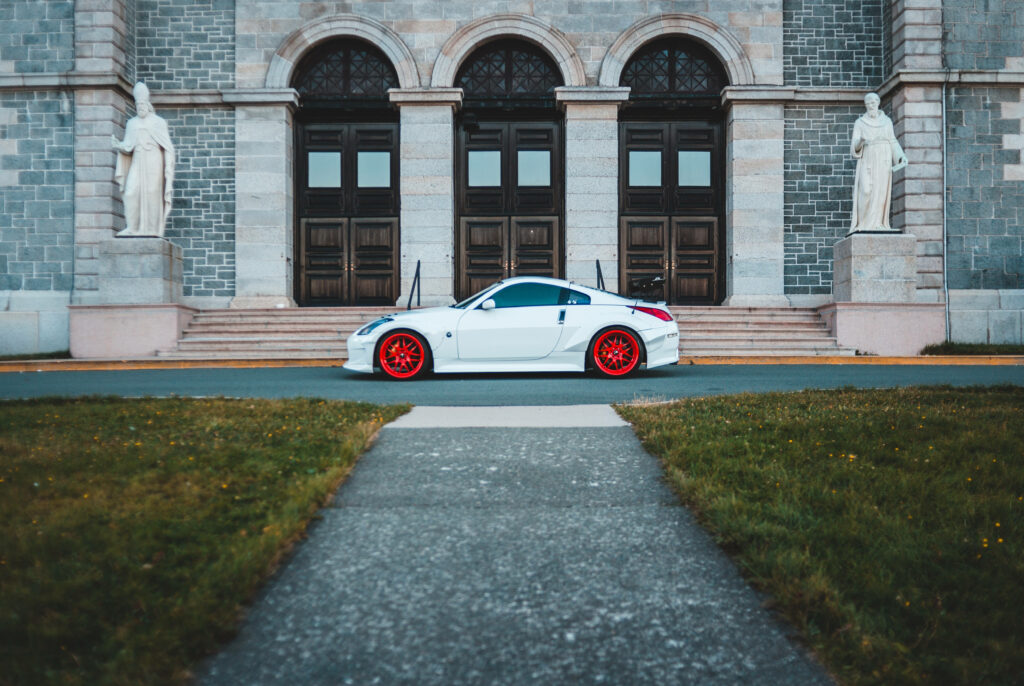 White sports car with red rims parked before grand stone estate luxury automotive wallpaper