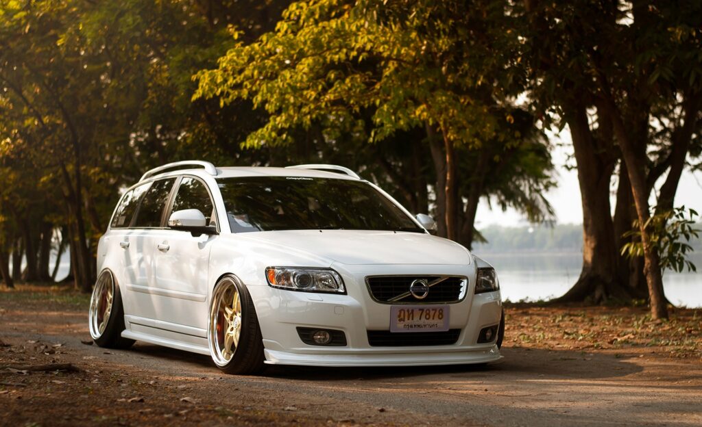 Modified White Volvo V50 in Serene Outdoor Setting with Lake View Wallpaper