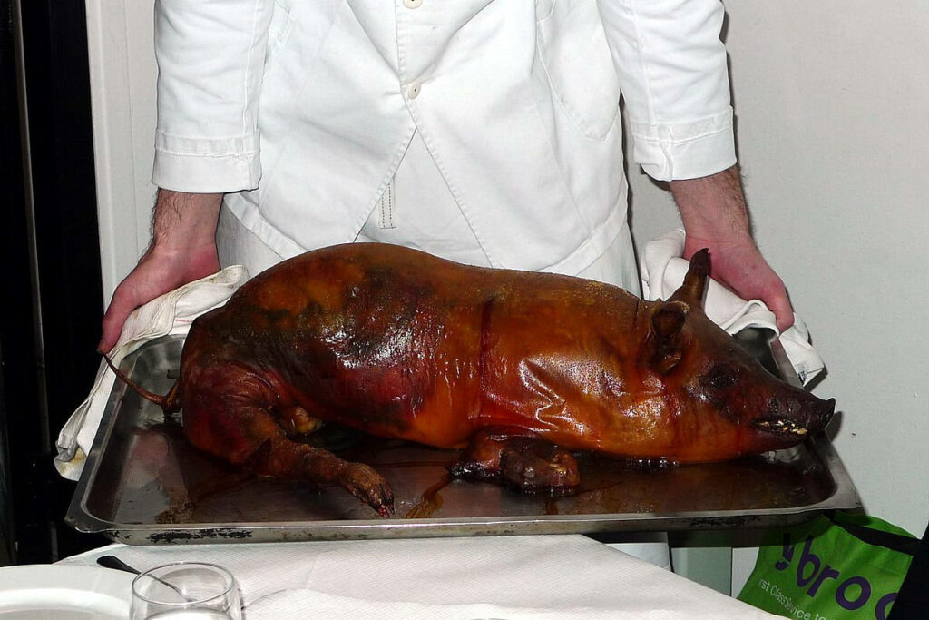 Chef Presents Whole Roasted Lechon: A Flavorful Culinary Delight Wallpaper