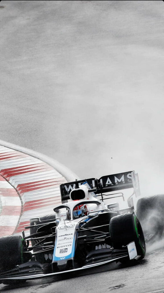 Williams Formula 1 car racing through wet corner spraying water on racetrack wallpaper background