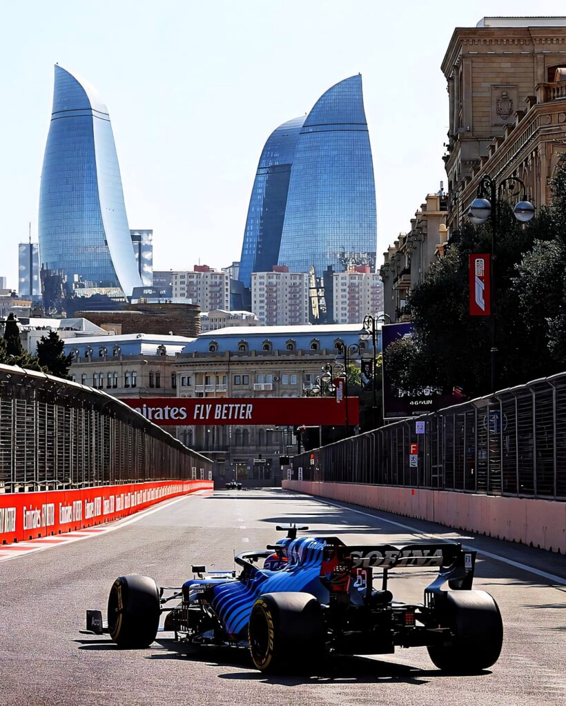 Williams sports car speeding on Baku streets with iconic Flame Towers in vibrant cityscape background Wallpaper