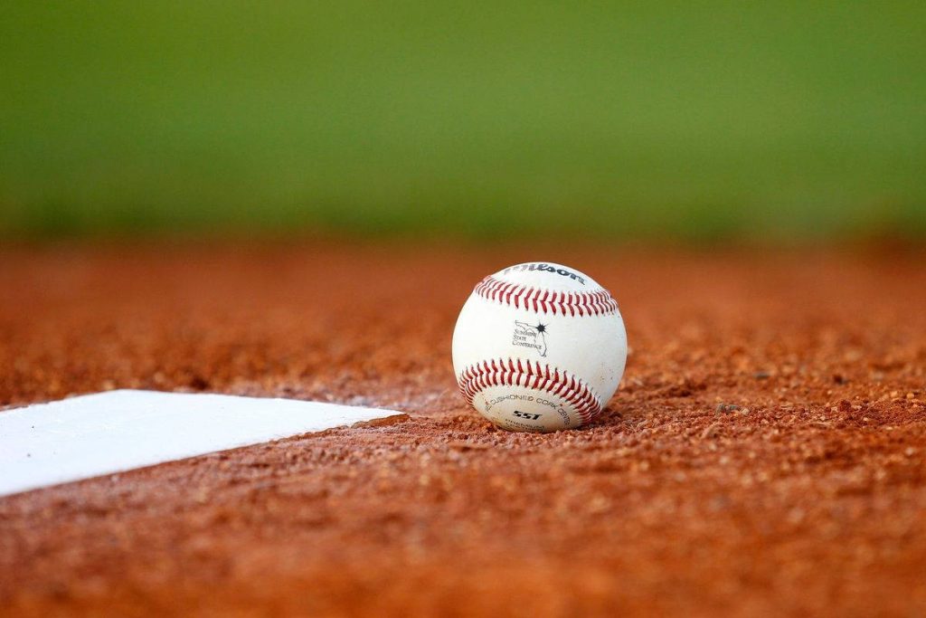 Wilson SST baseball on clay infield near base with soft green bokeh background wallpaper