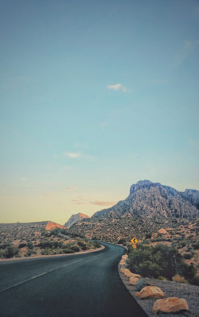 Winding road through rugged canyon with rocky mountains and clear blue sky wallpaper background