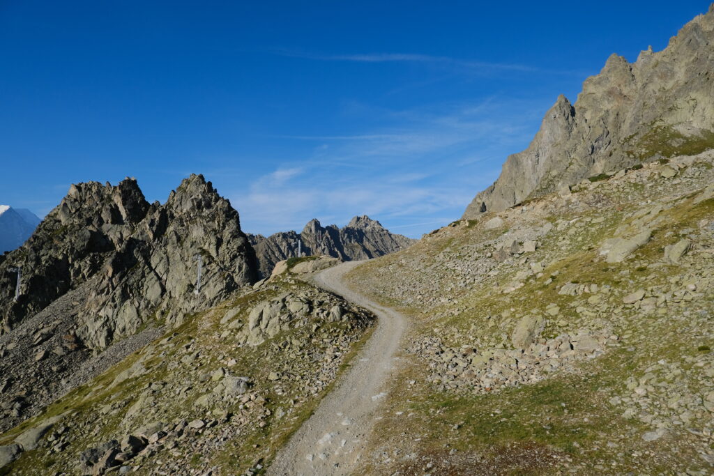 Winding mountain trail through rocky terrain and jagged peaks under clear blue sky wallpaper background