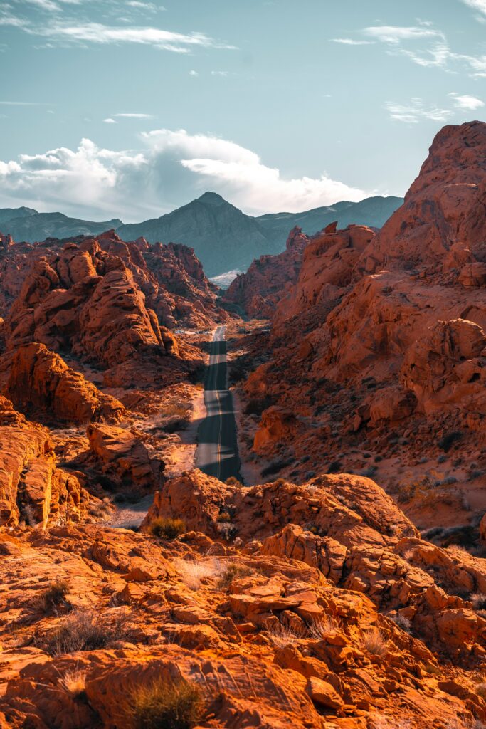 Aerial view of winding road in rocky valley with red orange mountains under clear blue sky wallpaper