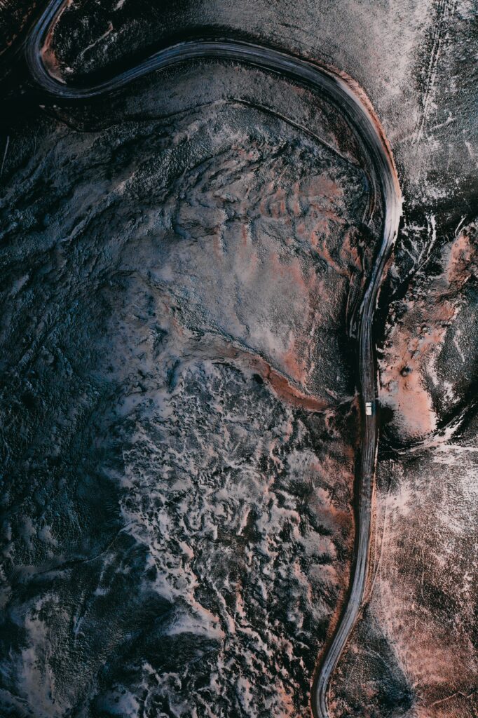 Aerial view of winding road through rugged earthy landscape with shadows nature wallpaper background