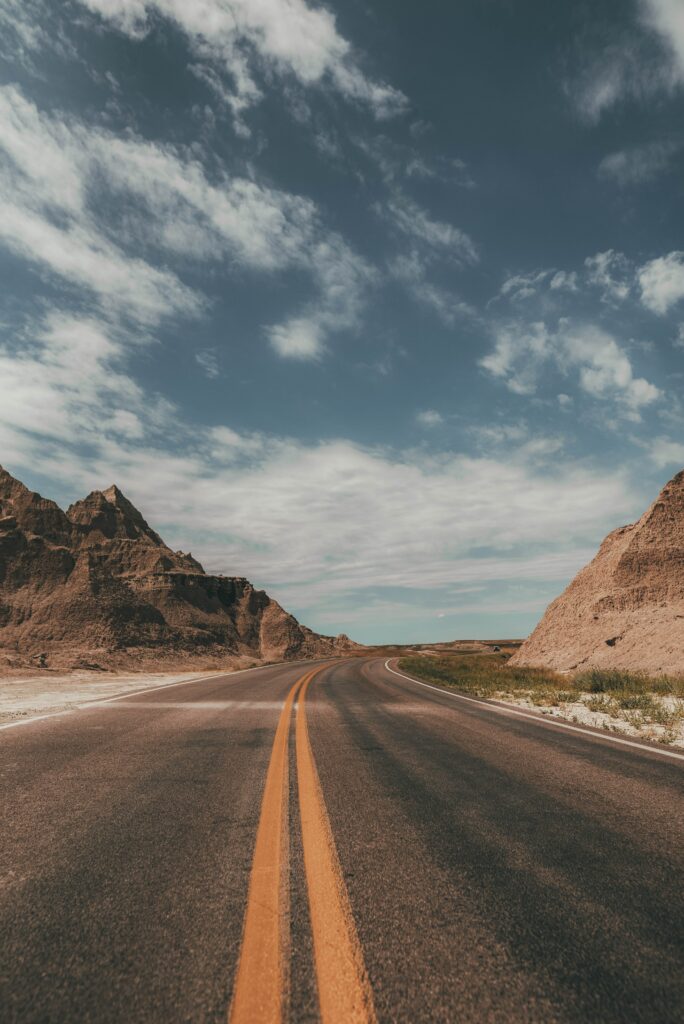 Winding road through rugged rocky terrain under vibrant sky with wispy clouds nature wallpaper