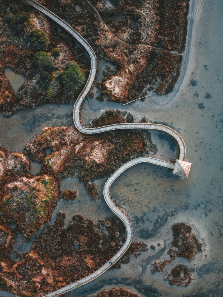 Aerial view of a winding wooden bridge over tranquil island waters with lush green vegetation Wallpaper