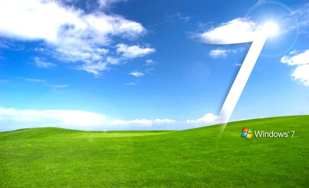Windows 7 default wallpaper with green hills blue sky and glowing white 7 graphic in clouds