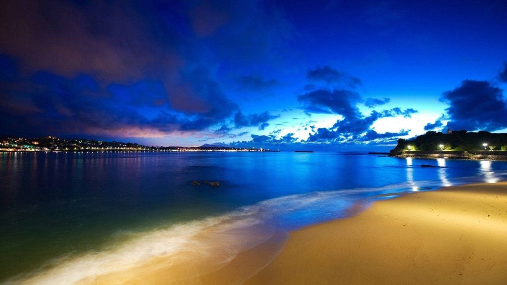 Windows Vista seascape wallpaper night beach twilight sky golden lights calm water reflection