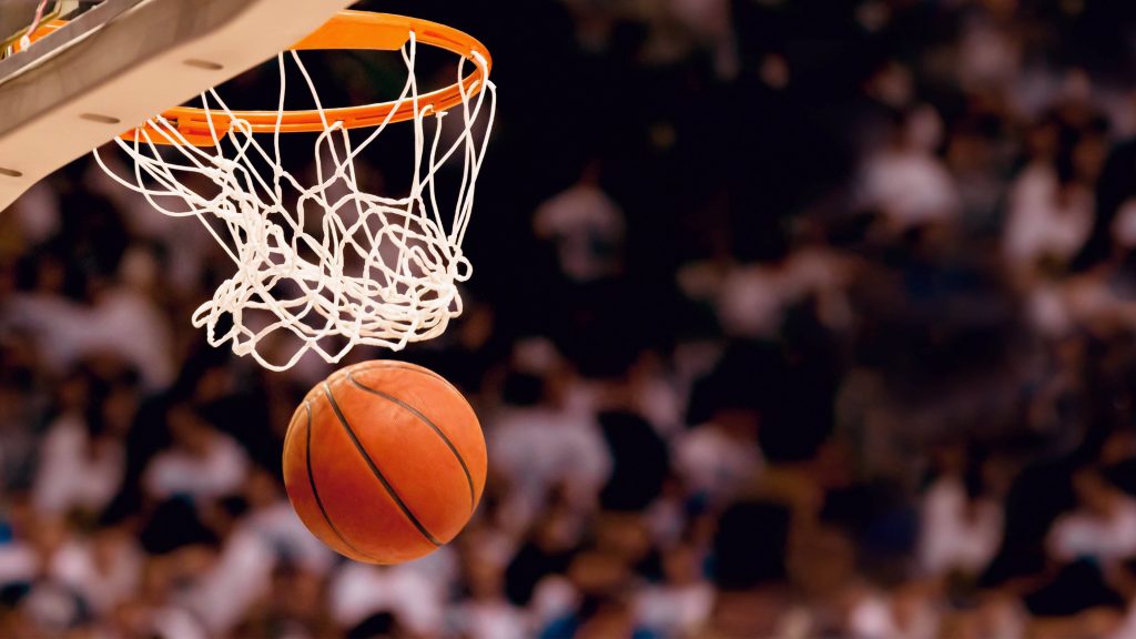 Basketball ball scoring through net with blurred crowd intense game moment wallpaper background